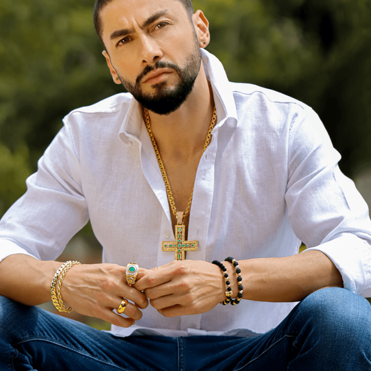 Cuello de hombre con cadena y dije de Cruz Sagrada en oro amarillo de 18 quilates con esmeraldas de color verde, hecho en Joyería Caracas.