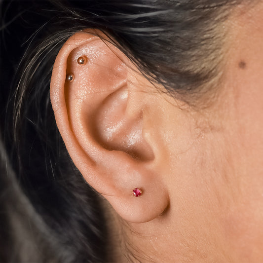 Oreja de mujer con topito en oro amarillo de 18 quilates y rubí natural de 2.75mm, hechos en Joyería Caracas.