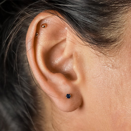 Oreja de mujer con topito en oro amarillo de 18 quilates y zafiro natural de 3.25mm, hechos en Joyería Caracas.