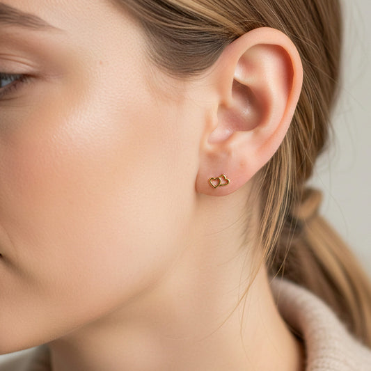 Oreja de modelo usando un topito en forma de corazón doble liso en oro amarillo de 18 quilates de Joyería Caracas.