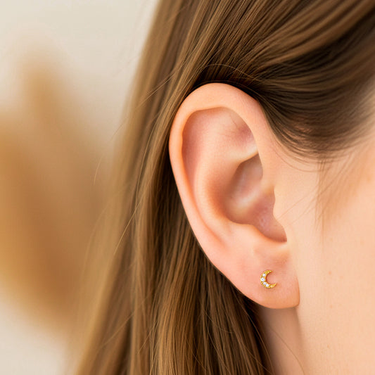 Oreja de modelo usando un topito en forma de luna en oro amarillo de 18 quilates con cristales de color blanco de Joyería Caracas.