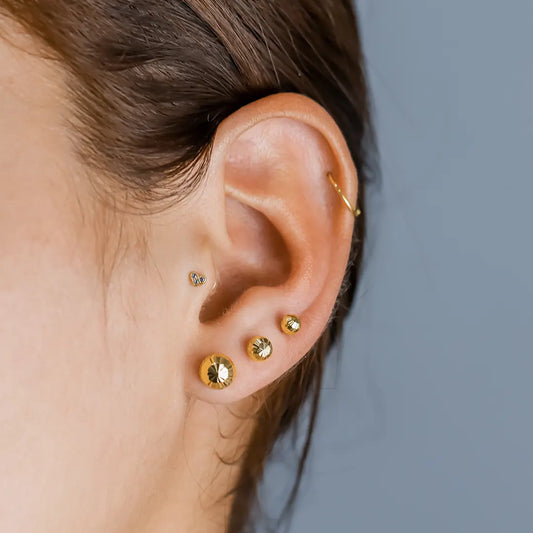 Oreja de mujer con topito en forma de corazón en oro amarillo de 18 quilates con 3 cristales de color blanco, hechos en Joyería Caracas.