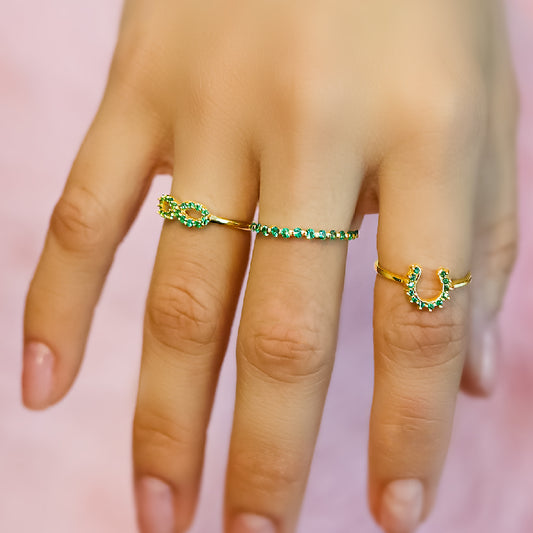 Mano de mujer con anillo en forma de infinito en oro amarillo de 18 quilates con cristales de color verde, hecho en Joyería Caracas.