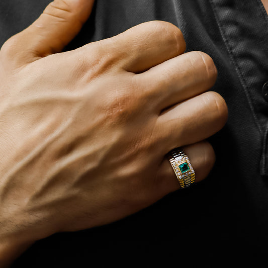 Mano de hombre con anillo Armis en oro amarillo y blanco de 18 quilates con esmeralda de color verde en el centro y cristales de color blanco alrededor, hecho en Joyería Caracas.