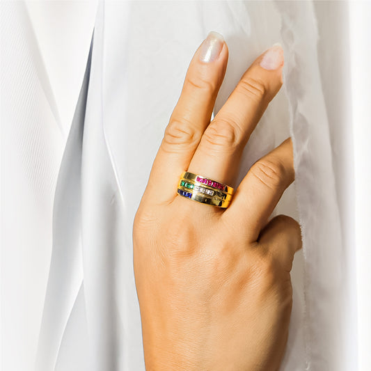 Mano de mujer con anillo en oro amarillo de 18 quilates con cristales de color blanco, azul y rosa, hecho en Joyería Caracas.