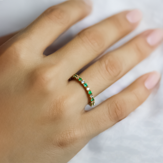 Mano de mujer con anillo en oro amarillo de 18 quilates con diamantes de color blanco y esmeraldas de color verde, hecho en Joyería Caracas.