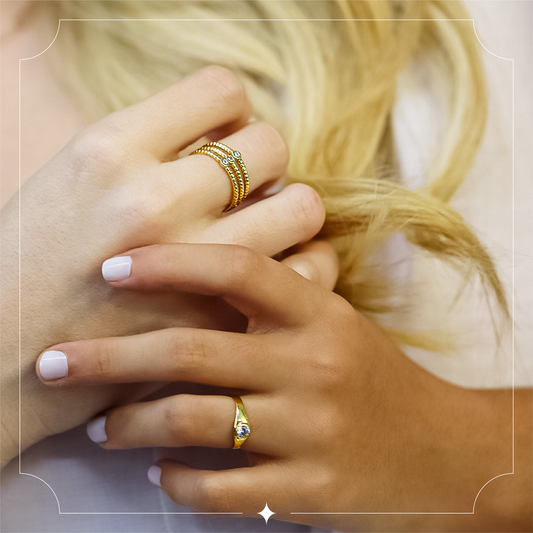 Mano de mujer con anillo de tres líneas en oro amarillo de 18 quilates con 3 cristales de color blanco, hecho en Joyería Caracas.