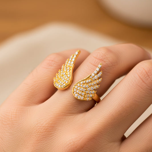 Mano de mujer usando un anillo con la forma de dos alas en oro amarillo de 18 quilates de Joyería Caracas.