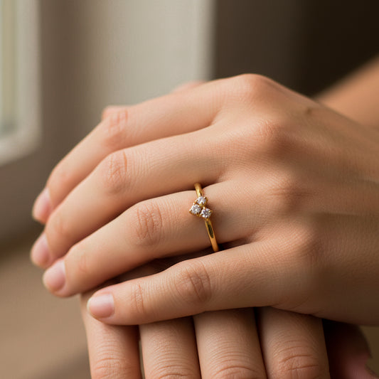 Mano de mujer usando un anillo en oro amarillo con forma de corazón en el centro de 18 quilates con 3 cristales de color blanco de Joyería Caracas.