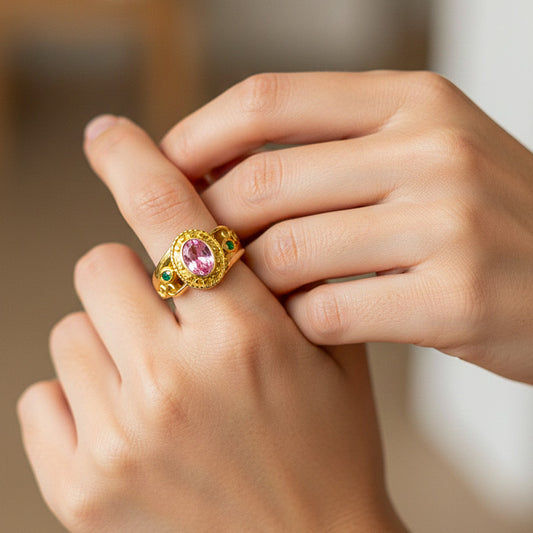 Mano de modelo usando un anillo de grado personalizado en oro amarillo de 18 quilates con cristal rosado en el centro y 2 verdes en los laterales de Joyería Caracas.