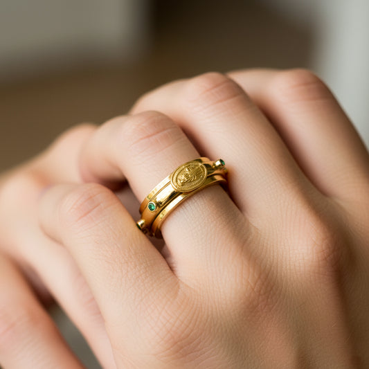 Mano de mujer usando un anillo denario con movimiento en oro amarillo de 18 quilates con Esmeraldas naturales de Joyería Caracas.