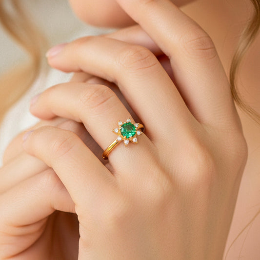Mano de modelo usando un anillo con forma de flor en oro amarillo de 18 quilates con Esmeralda y cristales de Joyería Caracas.