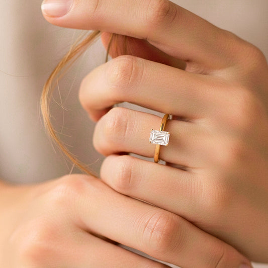 Mano de modelo usando un anillo en oro amarillo de 18 quilates con cristal en corte de baguette de Joyería Caracas.