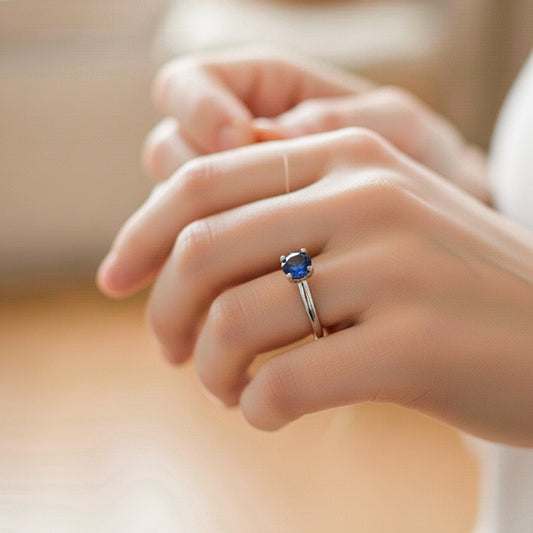 Mano de modelo usando un anillo en oro blanco de 18 quilates con piedra sintética Zafiro de Joyería Caracas.