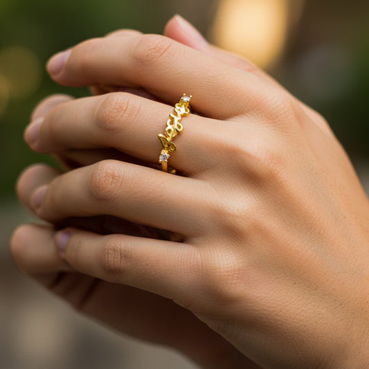 Mano de mujer usando un anillo con la palabra Jesús en el centro en oro amarillo de 18 quilates con 2 cristales a cada lado de color blanco de Joyería Caracas.