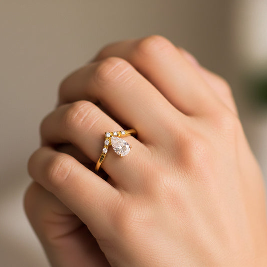 Mano de modelo usando un anillo en oro amarillo de 18 quilates con cristal en forma de lágrima en color blanco de Joyería Caracas.