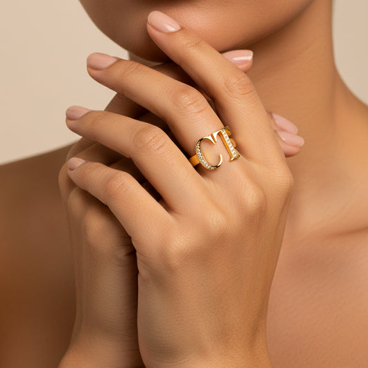 Mano de mujer usando un anillo de letras personalizadas en oro amarillo de 18 quilates y cristales de color blanco de Joyería Caracas.
