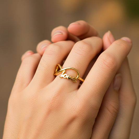 Mano de mujer usando un anillo con la forma de un infinito y la palabra love en oro amarillo de 18 quilates de Joyería Caracas.