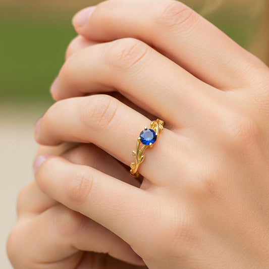 Mano de modelo usando un anillo con formas de ramas en oro amarillo de 18 quilates con Zafiro natural de Joyería Caracas.
