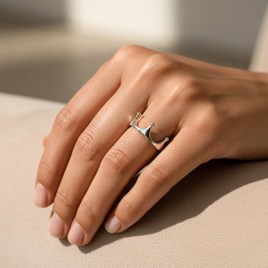 Mano de mujer usando un anillo con forma de corona en oro blanco de 18 quilates de Joyería Caracas.