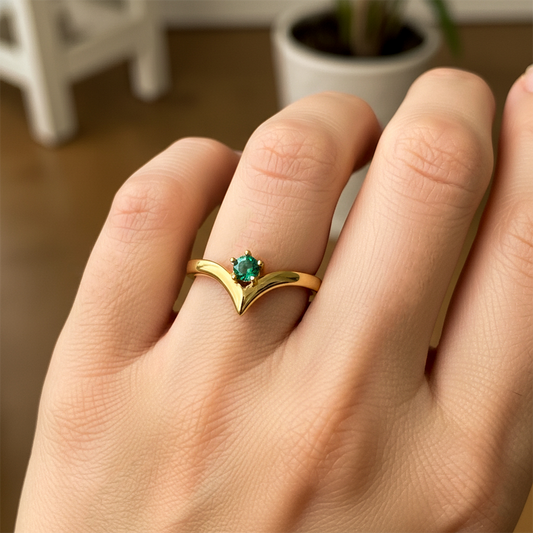 Mano de mujer usando un anillo en oro amarillo de 18 quilates con forma en punta con cristal de color verde de Joyería Caracas.