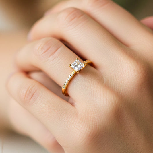 Mano de modelo usando un anillo princess en oro amarillo de 18 quilates con cristal de Joyería Caracas.