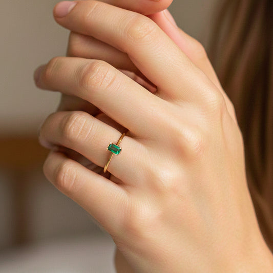 Mano de modelo usando un anillo en oro amarillo de 18 quilates con Esmeralda en corte baguette de Joyería Caracas.