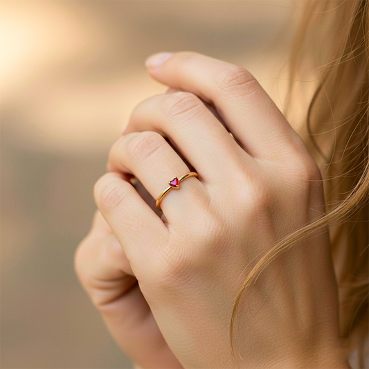 Mano de modelo usando un anillo de la colección Silent Spin en oro amarillo de 18 quilates con cristal en forma de corazón rojo de Joyería Caracas.