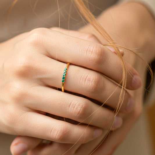 Mano de modelo usando un anillo en oro amarillo de 18 quilates con cristales verdes de Joyería Caracas.
