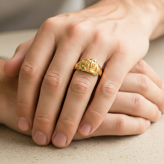 Mano de hombre usando un anillo con forma de tracto mula en el centro en oro amarillo de 18 quilates con cristales verdes de Joyería Caracas.
