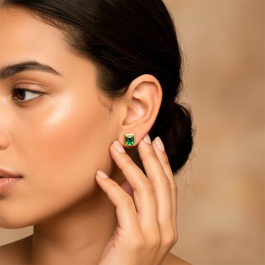 Oreja de modelo usando un topito cuadrado en oro amarillo de 18 quilates con Esmeralda de color verde de Joyería Caracas.