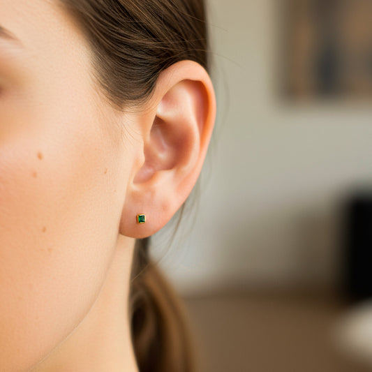 Oreja de modelo usando un topito en oro amarillo de 18 quilates con Esmeralda de Joyería Caracas.