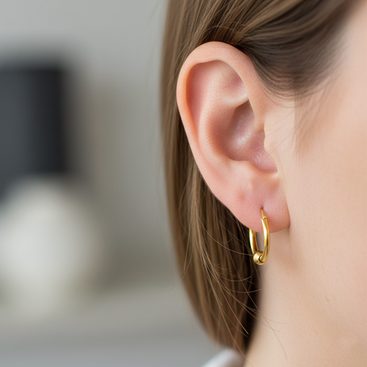 Oreja de modelo usando unos aretes sin fin con esfera lisa en oro amarillo de 18 quilates de Joyería Caracas.
