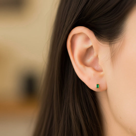 Oreja de modelo usando un topito en oro amarillo de 18 quilates con Esmeralda en corte baguette de Joyería Caracas.