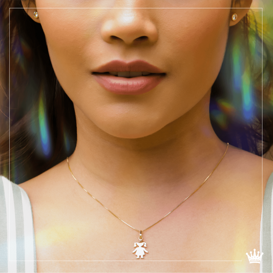 Cuello de modelo usando una cadena con un dije en forma de niña en oro amarillo de 18 quilates de Joyería Caracas.