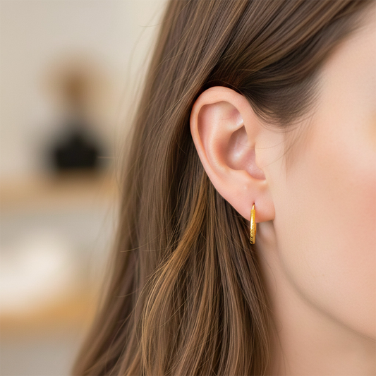 Oreja de modelo usando unas candongas tubo en oro amarillo de 18 quilates de Joyería Caracas.