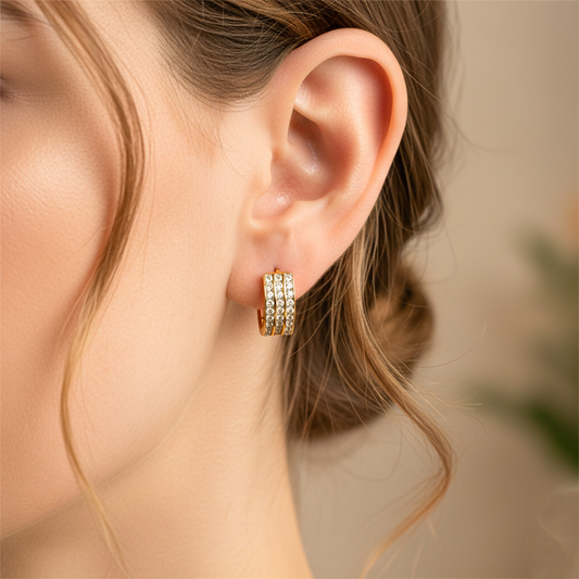 Oreja de modelo usando unas candongas huggies en oro amarillo de 18 quilates con cristales de Joyería Caracas.