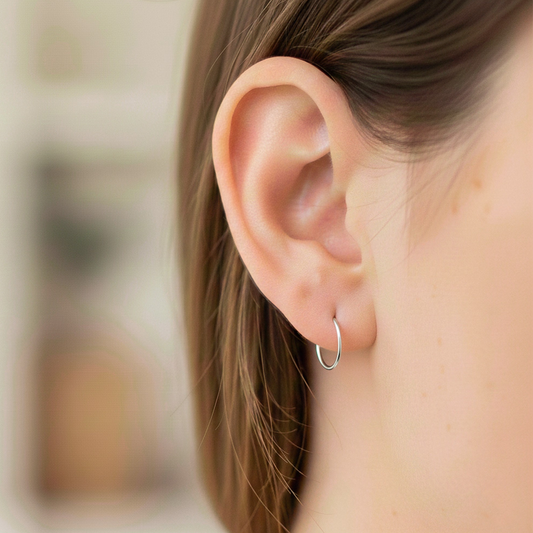 Oreja de modelo usando unas candongas sin fin en oro blanco de 18 quilates de Joyería Caracas.