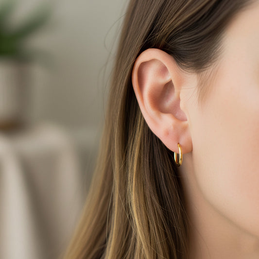 Oreja de modelo usando unas candongas medio tubo en oro amarillo de 18 quilates de Joyería Caracas.