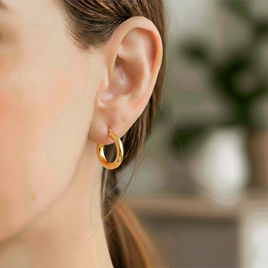 Oreja de modelo usando unas candongas tubo en oro amarillo de 18 quilates de Joyería Caracas.