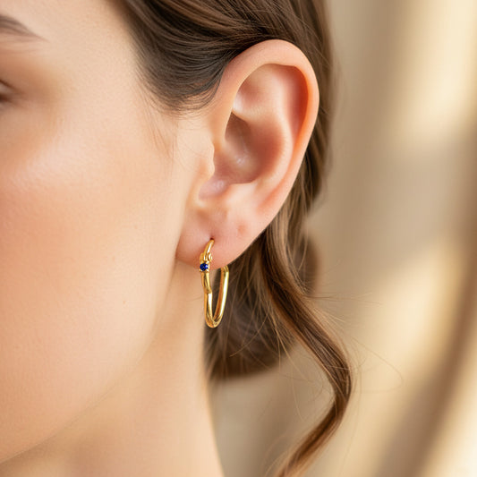 Oreja de modelo usando unas candongas en forma de corazón tubo en oro amarillo de 18 quilates con cristal de Joyería Caracas.