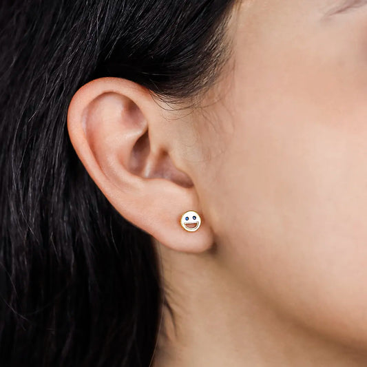 Oreja de mujer con topito en forma de carita feliz en oro amarillo de 18 quilates y con dos cristales de color azul en los ojos, hecho en joyeria caracas.