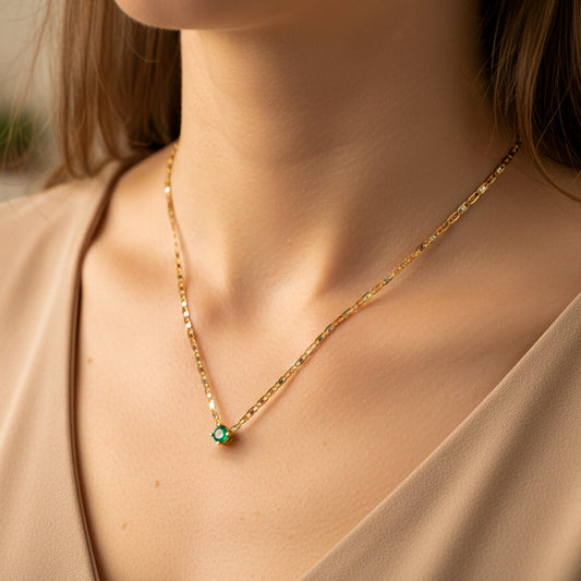 Cuello de mujer usando una gargantilla de cadena escalera 3 oros de 18 quilates con dije pasante Esmeralda de Joyería Caracas.