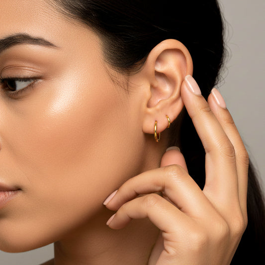 Oreja de mujer usando un piercing en forma de aro en oro amarillo de 18 quilates de Joyería Caracas.