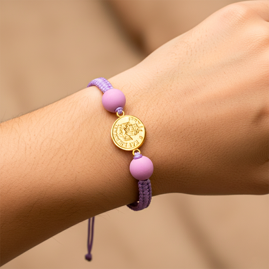 Mano de modelo usando una pulsera tejida en hilo color lila con herraje de Árcangel San Rafael de Joyería Caracas.