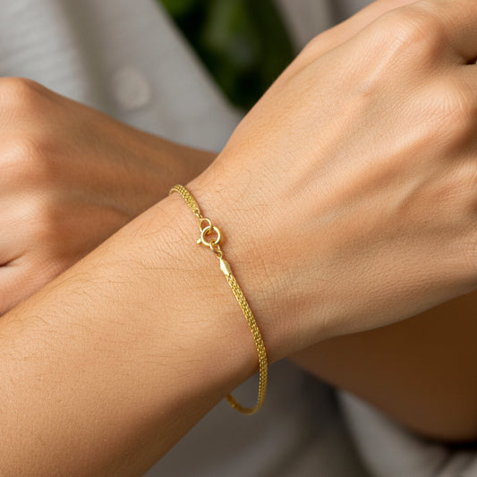 Mano de mujer usando una pulsera en tejido bismarck en oro amarillo de 18 quilates de Joyería Caracas.