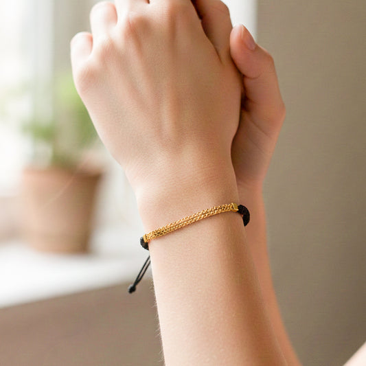 Mano de modelo usando un pulsera tejida en hilo color negro con herraje de esterilla bismarck en oro 18 quilates de Joyería Caracas.