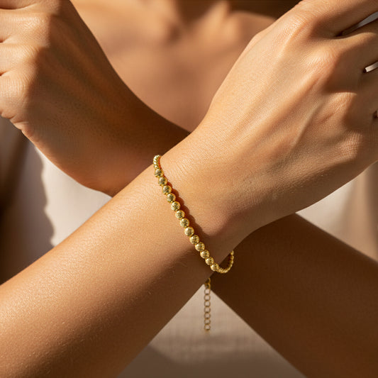 Mano de mujer usando una pulsera con esferas diamantadas sin fin en oro amarillo de 18 quilates de Joyería Caracas.