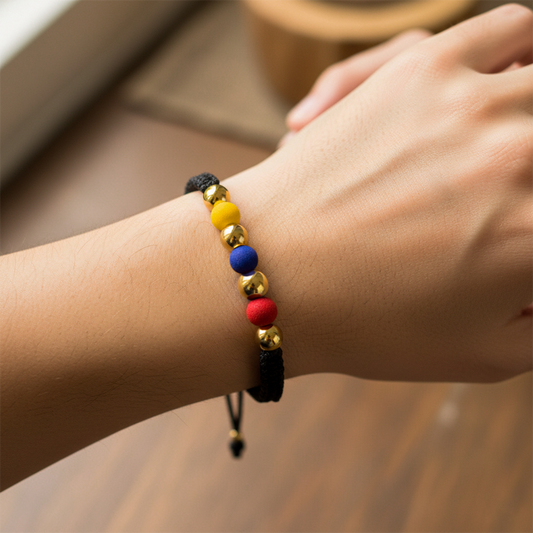 Mano de modelo usando una pulsera tejida en hilo color negro, con esferas lisas en oro amarillo de 18 quilates y bisutería de calidad de Joyería Caracas.