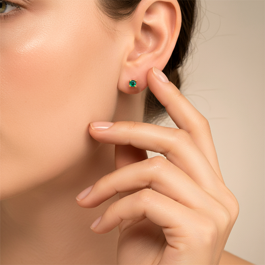 Oreja de modelo usando un topito en oro amarillo de 18 quilates con Esmeralda redonda de Joyería Caracas.